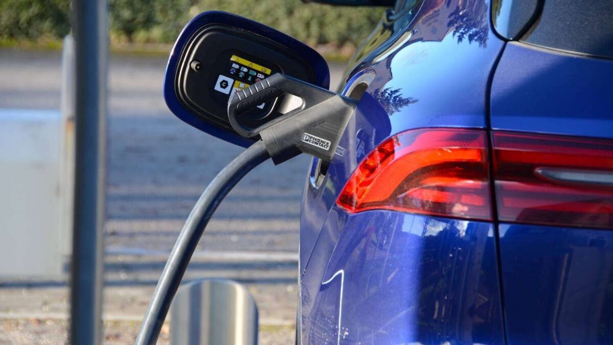 صورة تعبيرية لأسطول مركبات كهربائية يشمل سيارات وشاحنات أمام شعارات EV100 وأسترازينيكا