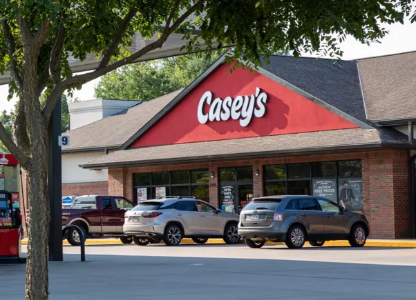 صورة لمحطة وقود تحمل لافتات Casey's General Stores وParker's Kitchen وYesway مع إبراز خطط التوسع والاستحواذ الأمريكية.